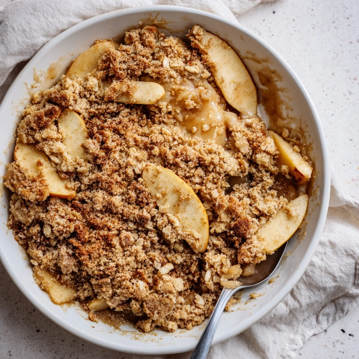 Warm, rustic apple and cinnamon crumble, glistening after baking, ready to be enjoyed warm.