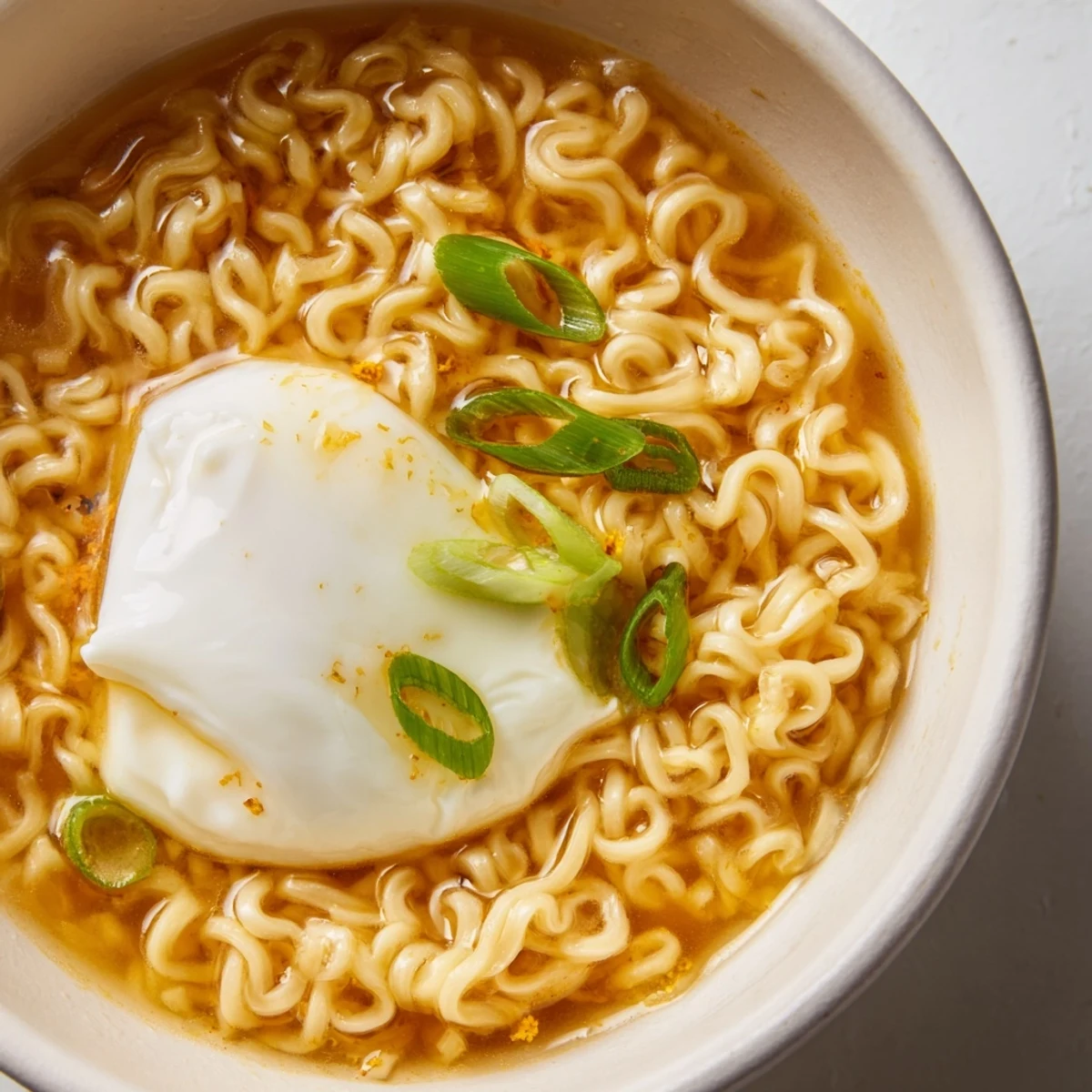 Close-up of fluffy egg atop upgraded instant ramen, highlighting the rich broth's flavorful essence.
