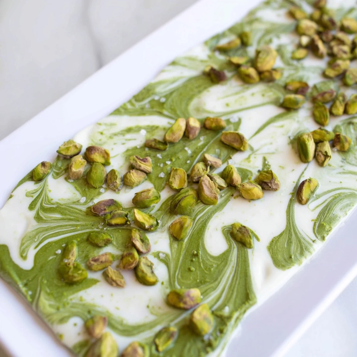 A close-up of a delicious Pistachio Matcha White Chocolate bark, showing the vibrant green matcha powder.