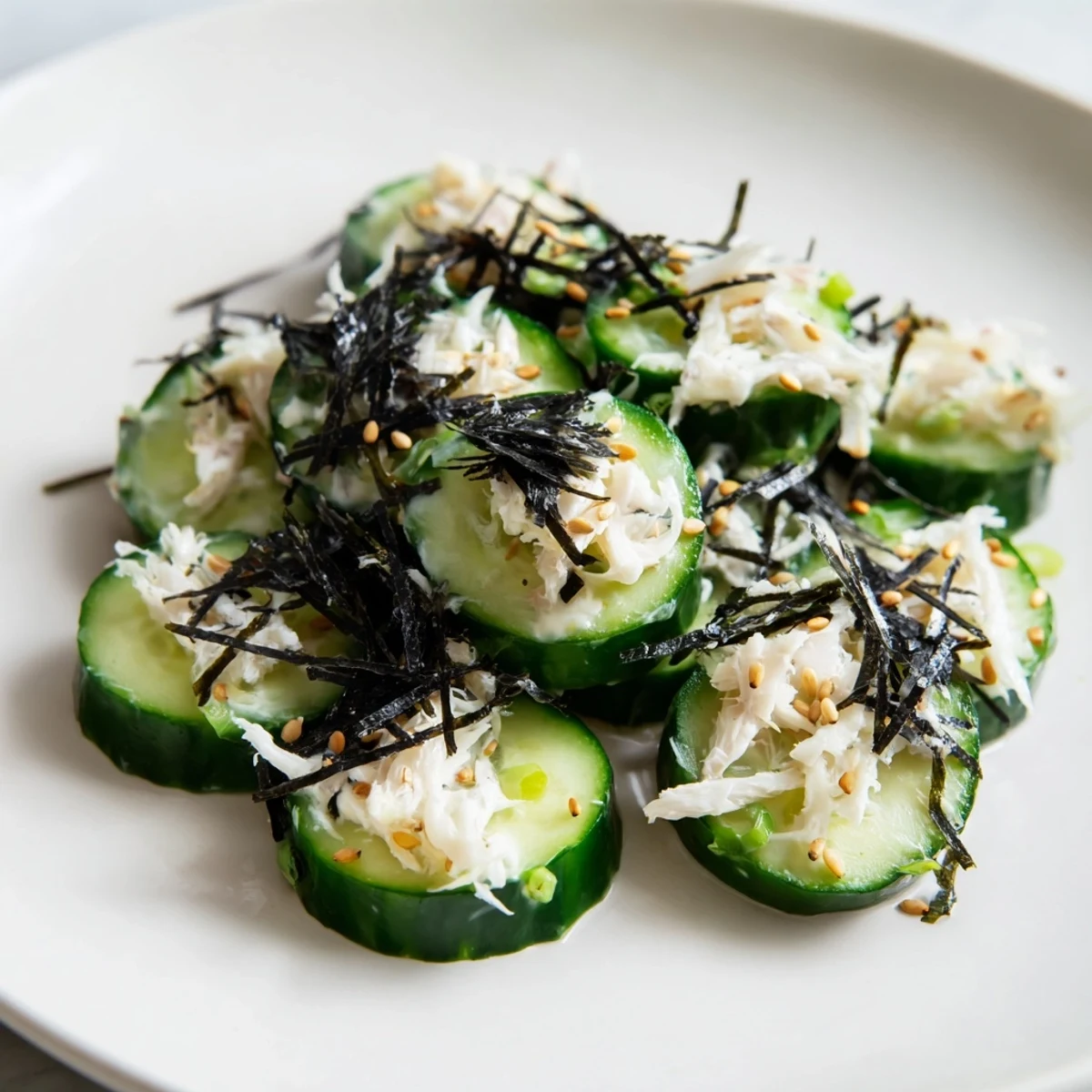 Creamy California Roll Cucumber Salad with crisp veggies, imitation crab, and sesame seeds served in a white bowl.