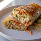 Garlicky Pulled Chicken Wraps served warm on a platter with lemon wedges, showcasing golden, pan-fried exteriors and vibrant lettuce, carrot, and cucumber fillings.