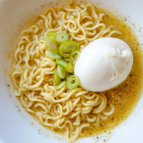 Savory photo of upgraded instant ramen with a perfectly cooked soft egg and vibrant scallions.