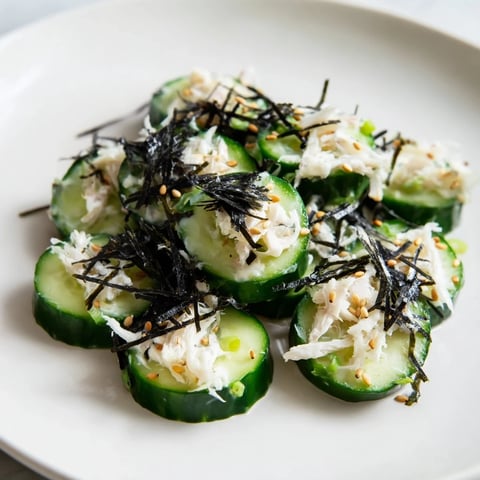 Creamy California Roll Cucumber Salad with crisp veggies, imitation crab, and sesame seeds served in a white bowl.