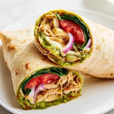 Delicious pesto chicken wrap, featuring shredded chicken with a zesty pesto flavor, ready to serve as lunch.