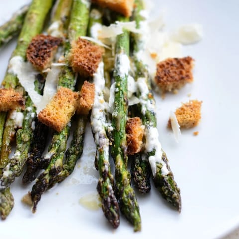 Roasted asparagus Caesar salad on a white plate with charred spears, crisp romaine, and homemade croutons.
