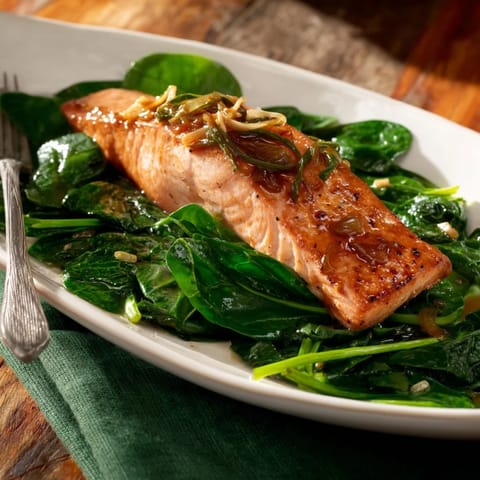 Tender miso salmon fillets rest on a bed of wilted spinach, ready to serve for dinner.