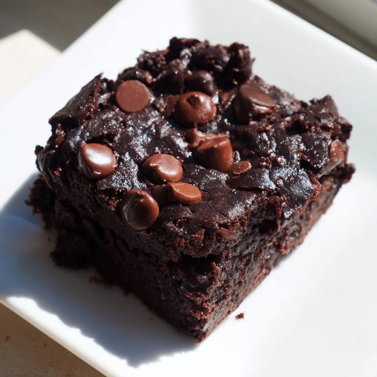A square of decadent Greek yogurt brownies, boasting a moist center and chocolate chips.