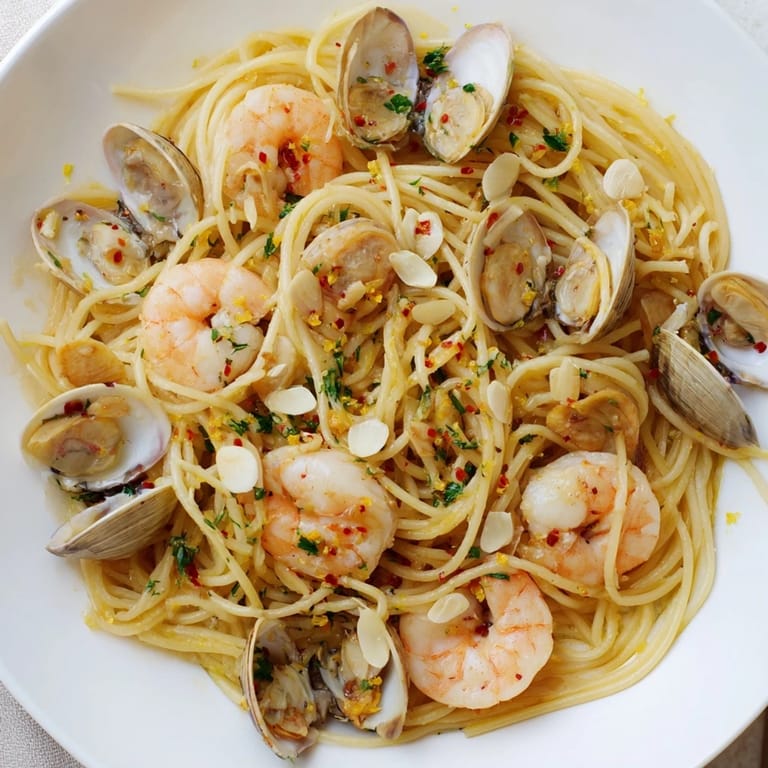 Sizzling shrimp and clams in Seafood Pasta Aglio e Olio, finished with fresh parsley and lemon.