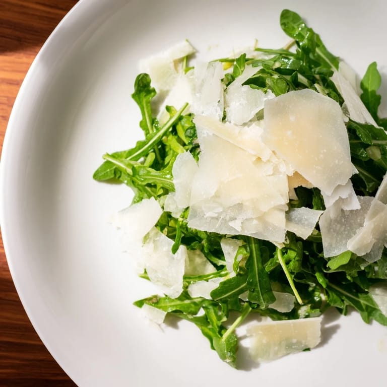 A beautiful bowl of Italian arugula salad, tossed with vibrant lemon dressing and Parmesan.