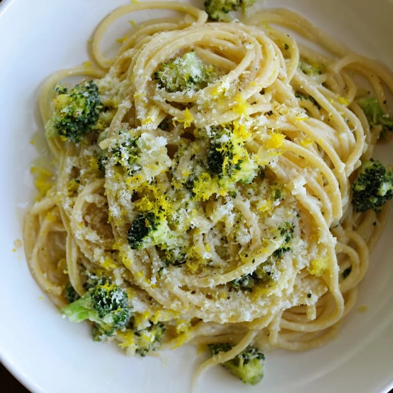 A bright spring One-Pot Lemon Broccoli Pasta garnished with fresh basil and extra Parmesan, with lemon wedges on the side for a zesty finish.