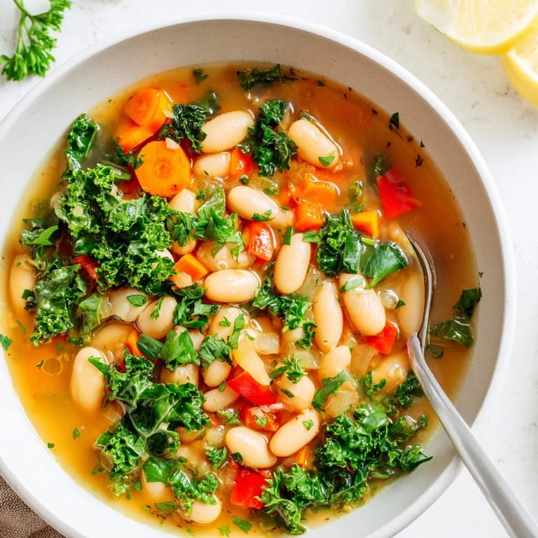A hearty Mediterranean White Bean Stew simmering in a pot, with colorful vegetables and a rich olive oil broth ready to serve.