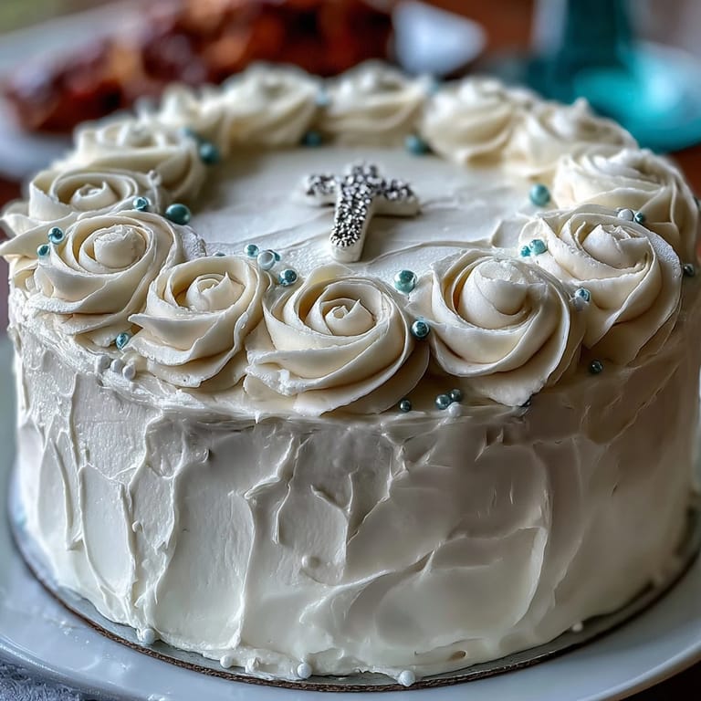 Elegant First Communion Cake with delicate white fondant roses, smooth buttercream frosting, and a silver cross centerpiece, perfect for a sacred celebration.